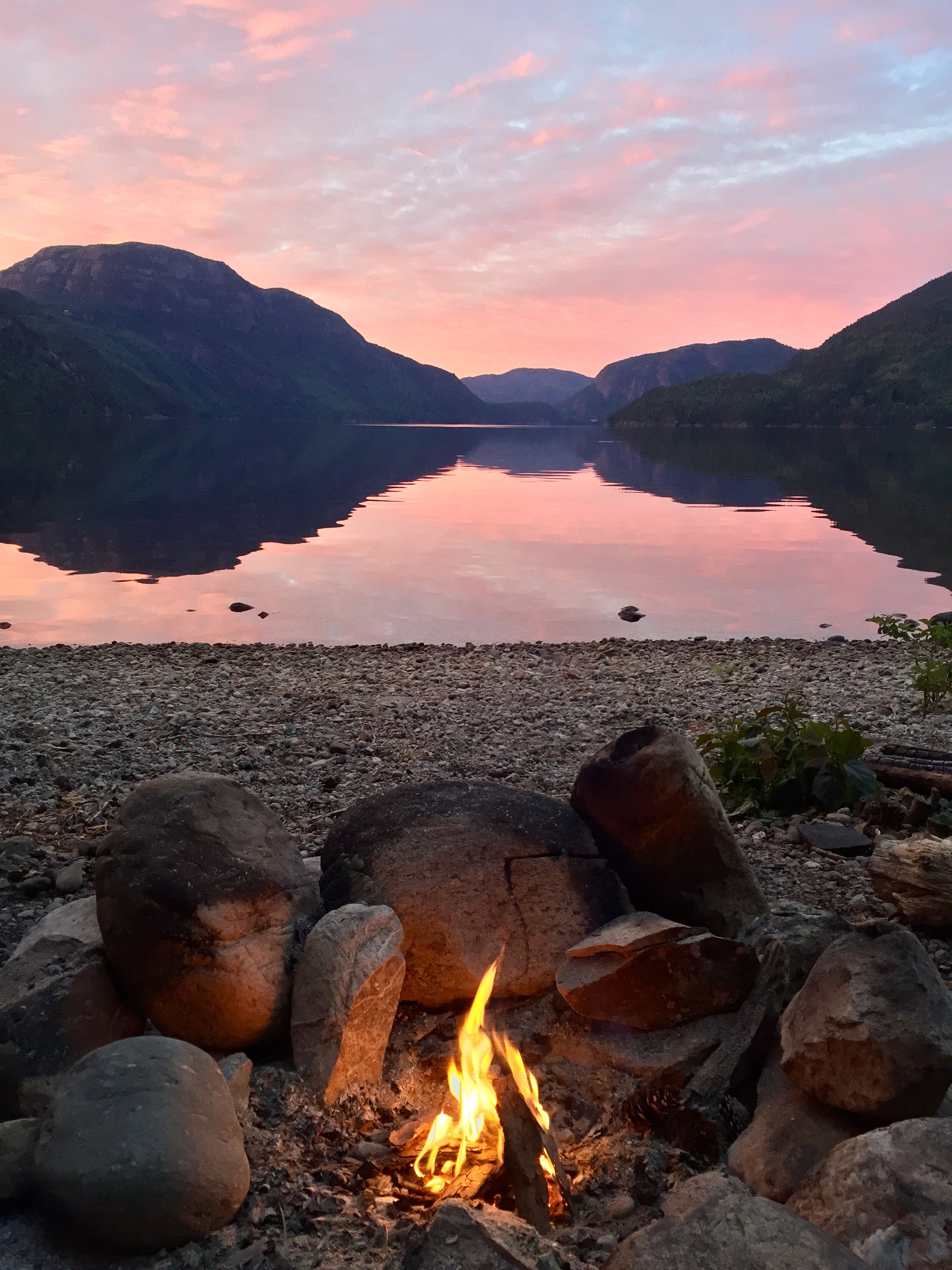 A campfire, looking out over the water early in the morning